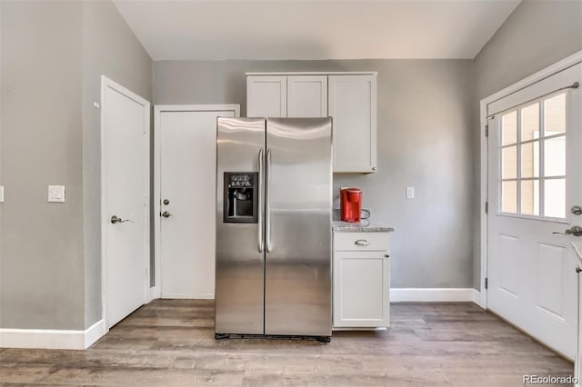 kitchen with stainless steel fridge, light hardwood / wood-style floors, and white cabinets