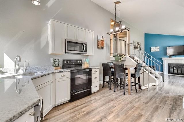 kitchen featuring black range with electric cooktop, light hardwood / wood-style floors, sink, and white cabinets