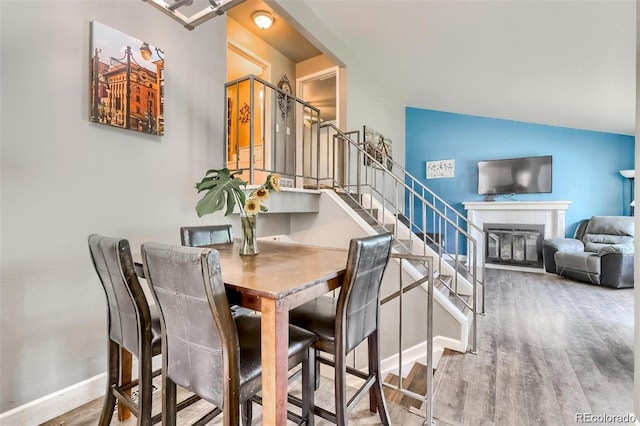 dining space with lofted ceiling, hardwood / wood-style floors, and a fireplace