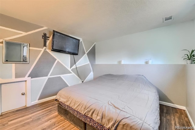 bedroom with wood-type flooring and a textured ceiling