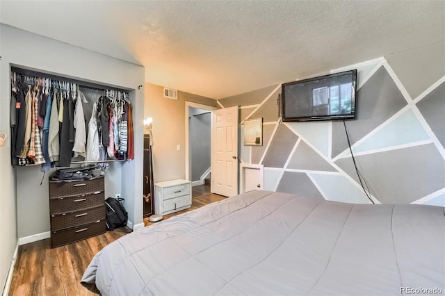 bedroom with dark wood-type flooring, a textured ceiling, and a closet