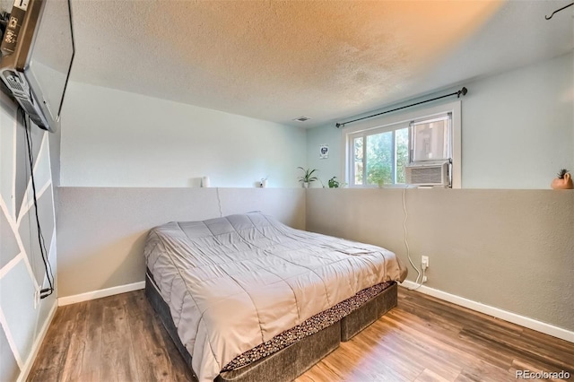 bedroom featuring cooling unit, a textured ceiling, and dark hardwood / wood-style flooring