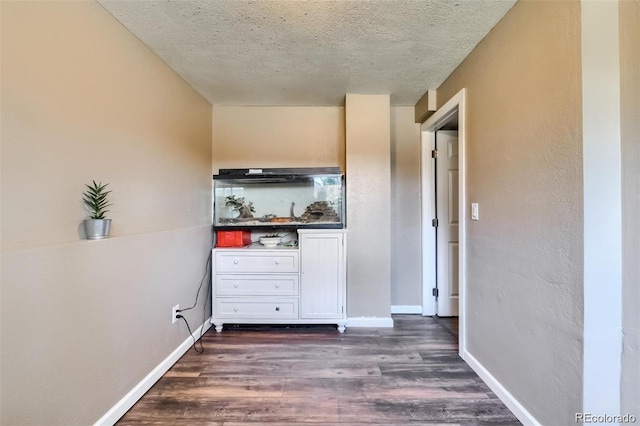 hallway with a textured ceiling and dark hardwood / wood-style flooring