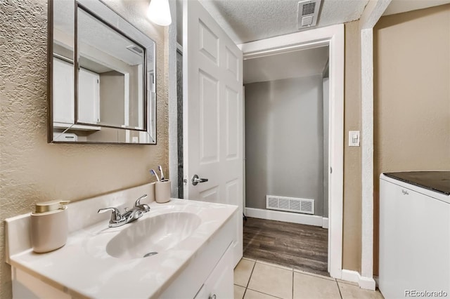 bathroom with tile patterned flooring, vanity, washer / clothes dryer, and a textured ceiling