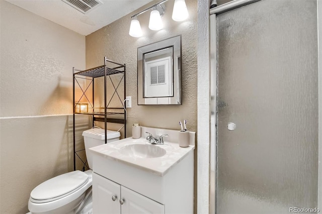 bathroom featuring vanity, toilet, and a shower with door