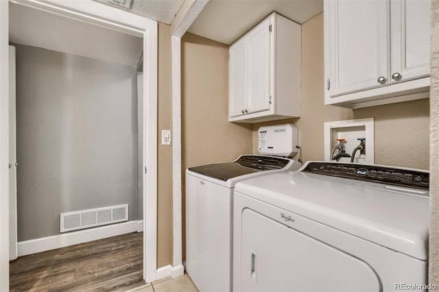 washroom with cabinets, light hardwood / wood-style floors, and washing machine and dryer