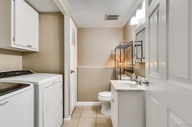 clothes washing area featuring sink, light tile patterned floors, washing machine and dryer, and a textured ceiling