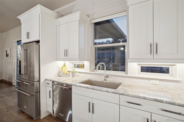 kitchen with white cabinets, light stone counters, stainless steel appliances, sink, and dark hardwood / wood-style floors