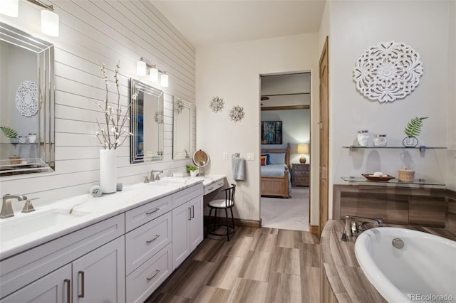 bathroom featuring wood-type flooring, tiled bath, and vanity