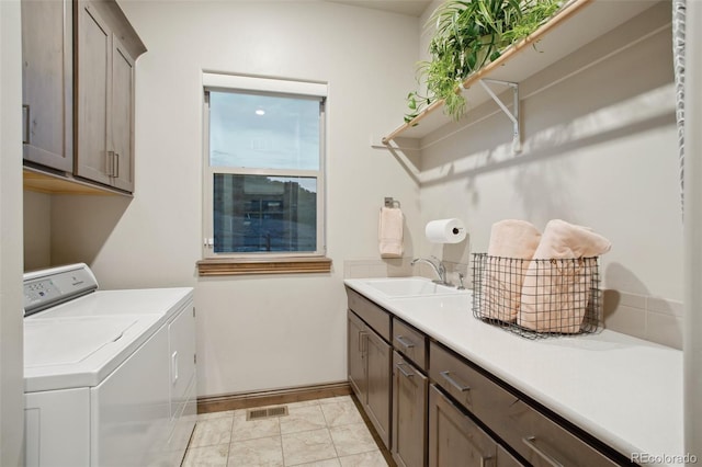 laundry area with light tile patterned floors, cabinets, independent washer and dryer, and sink