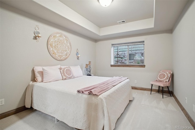 carpeted bedroom featuring a raised ceiling