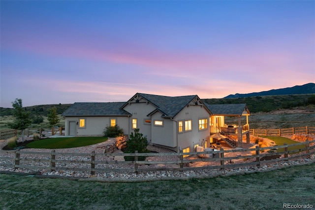 back house at dusk with a lawn, a mountain view, and a playground