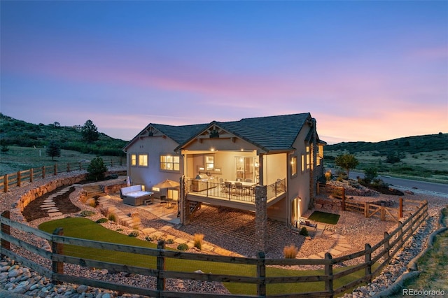 back house at dusk featuring a mountain view and a patio