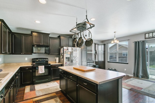9919 Memphis St, Commerce City, CO 80022 - kitchen with black appliances, dark wood-type flooring, light countertops, a kitchen island, and recessed lighting