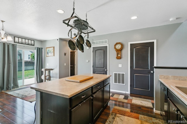 9919 Memphis St, Commerce City, CO 80022 - kitchen with dark wood-style flooring, light countertops, a kitchen island, recessed lighting, and a textured ceiling