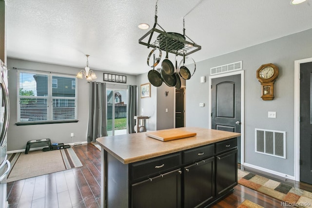 9919 Memphis St, Commerce City, CO 80022 - kitchen featuring dark wood-style floors, baseboards, a chandelier, dark cabinetry, and a textured ceiling