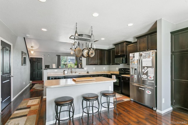 9919 Memphis St, Commerce City, CO 80022 - kitchen featuring black appliances, a sink, dark wood-type flooring, light countertops, and a kitchen breakfast bar