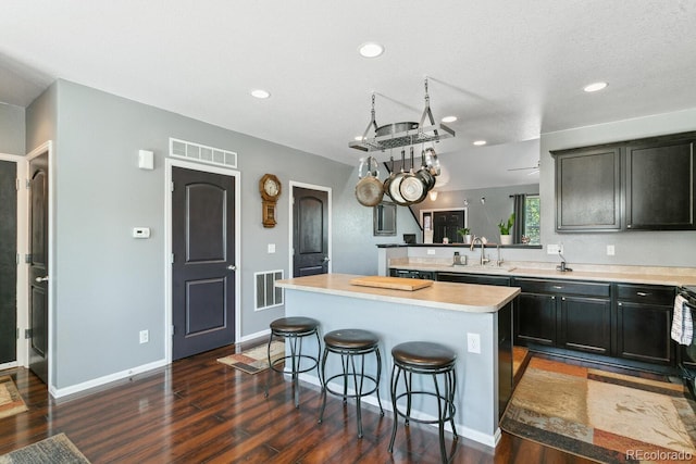 9919 Memphis St, Commerce City, CO 80022 - kitchen with dark wood-style flooring, a kitchen bar, light countertops, a kitchen island, and recessed lighting