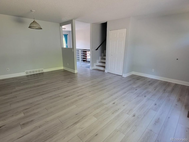 unfurnished room featuring light hardwood / wood-style floors and a textured ceiling