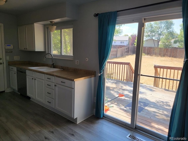 kitchen featuring black dishwasher, sink, hardwood / wood-style flooring, and white cabinetry