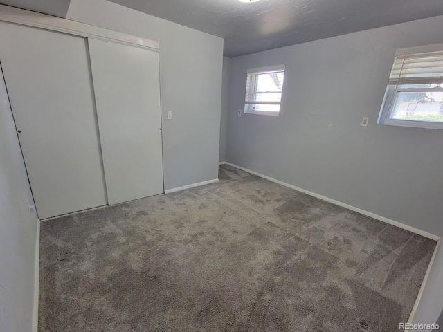 unfurnished bedroom with a closet, multiple windows, and carpet flooring