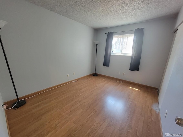 spare room featuring light hardwood / wood-style floors and a textured ceiling