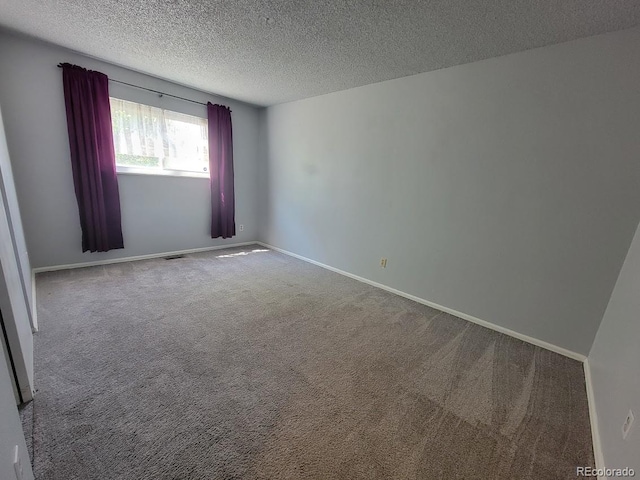 carpeted empty room featuring a textured ceiling