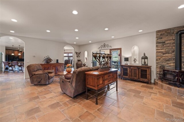 28098 Green Valley Ln, Conifer, CO 80433 - living room with arched walkways, a wood stove, recessed lighting, and stone tile floors