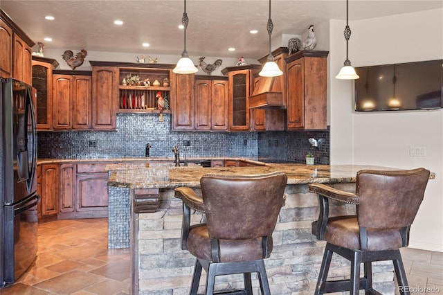28098 Green Valley Ln, Conifer, CO 80433 - kitchen featuring black fridge, stone counters, a kitchen bar, glass insert cabinets, and backsplash