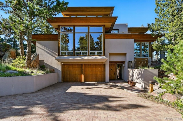 9041 Eastridge Rd, Golden, CO 80403 - contemporary home with stucco siding, decorative driveway, and an attached garage