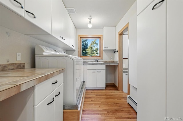 9041 Eastridge Rd, Golden, CO 80403 - washroom featuring baseboard heating, washer and dryer, light wood-style floors, and a sink