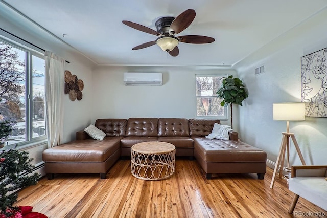 living room featuring light wood-type flooring, a wall mounted air conditioner, ceiling fan, and plenty of natural light