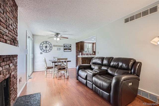 9630 W 104th Ave, Broomfield, CO 80021 - living area with a ceiling fan, light wood-style floors, healthy amount of natural light, a textured ceiling, and a fireplace