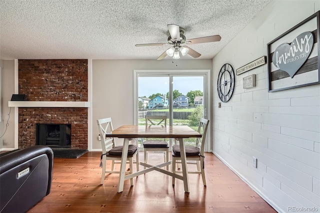 9630 W 104th Ave, Broomfield, CO 80021 - dining space with a textured ceiling, a ceiling fan, wood finished floors, and a fireplace