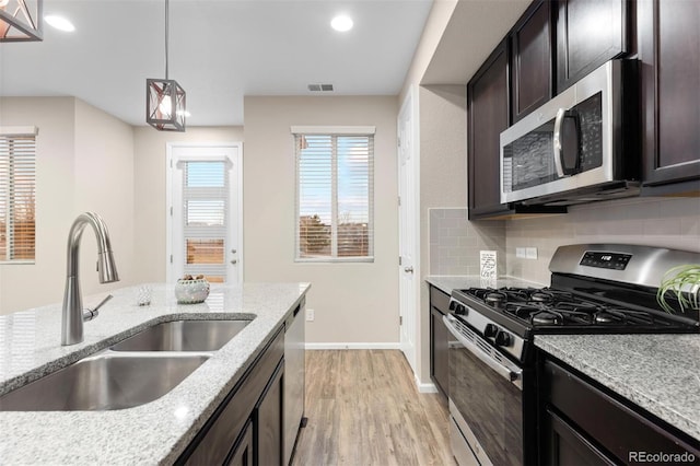 23630 E 5th Pl, Aurora, CO 80018 - kitchen with stainless steel appliances, light wood finished floors, backsplash, recessed lighting, and dark brown cabinetry