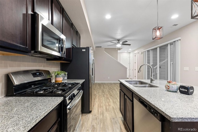 23630 E 5th Pl, Aurora, CO 80018 - kitchen featuring appliances with stainless steel finishes, light wood finished floors, tasteful backsplash, a ceiling fan, and an island with sink