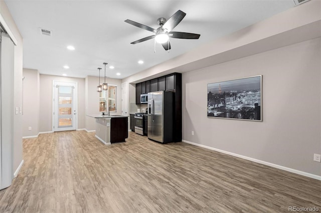 kitchen with sink, stainless steel appliances, pendant lighting, a kitchen island, and hardwood / wood-style flooring