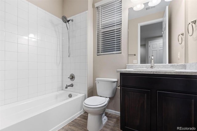 full bathroom with vanity, tiled shower / bath combo, hardwood / wood-style flooring, and toilet