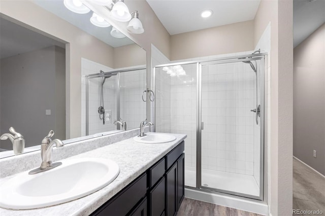 bathroom with hardwood / wood-style floors, vanity, and a shower with shower door