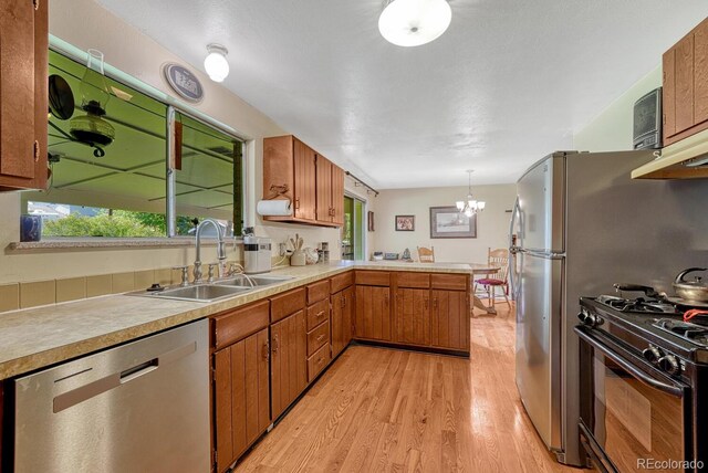 7479 Pierce St, Arvada, CO 80003 - kitchen with dishwasher, black range with gas cooktop, light wood-style floors, light countertops, and a peninsula