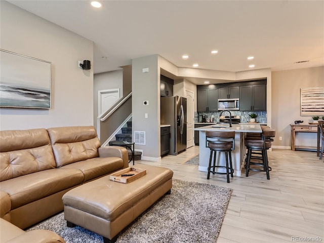 living room with recessed lighting, visible vents, light wood-style flooring, and baseboards