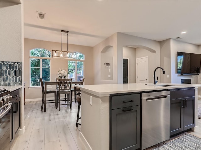 kitchen with stainless steel appliances, light countertops, a sink, and light wood finished floors