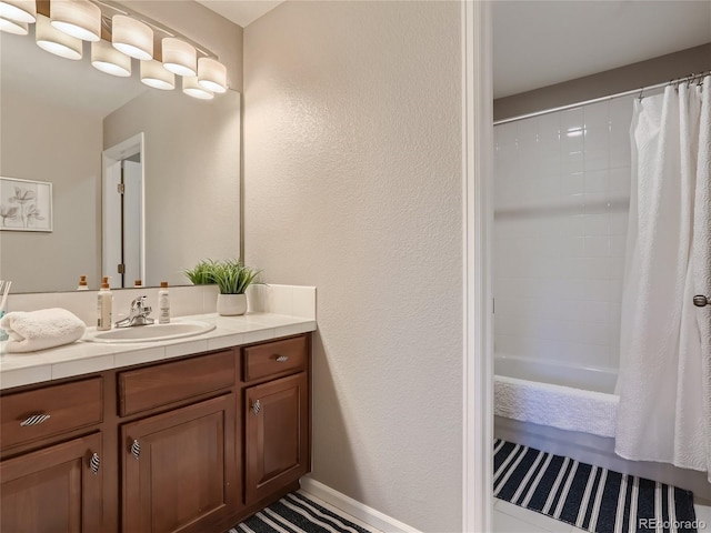 full bathroom with a textured wall, shower / tub combo with curtain, and vanity