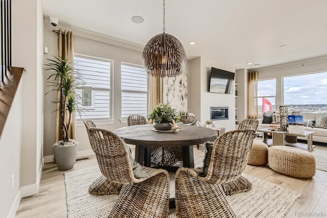 17719 Prairie Peak Trl, Parker, CO 80134 - dining area featuring light wood-type flooring, a glass covered fireplace, baseboards, and recessed lighting