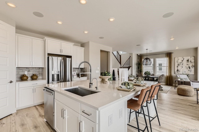 17719 Prairie Peak Trl, Parker, CO 80134 - kitchen with a sink, appliances with stainless steel finishes, open floor plan, light wood finished floors, and a kitchen island with sink