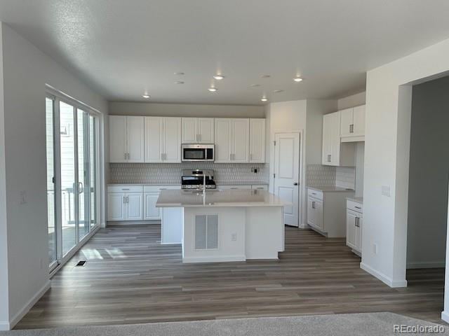 17719 Prairie Peak Trl, Parker, CO 80134 - kitchen with stainless steel microwave, range, plenty of natural light, white cabinets, and recessed lighting