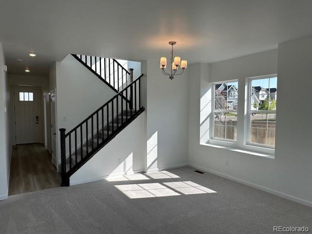 17719 Prairie Peak Trl, Parker, CO 80134 - unfurnished living room with carpet floors, a chandelier, stairway, and recessed lighting