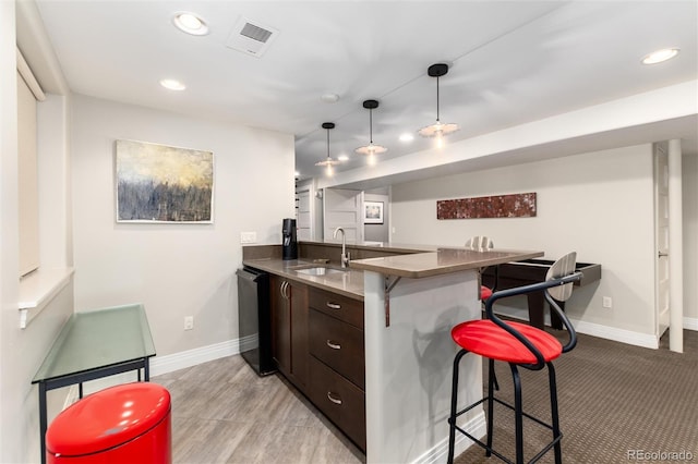 kitchen with dishwasher, sink, a breakfast bar area, kitchen peninsula, and dark brown cabinets