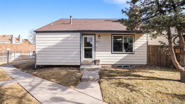 view of front of home featuring entry steps, roof with shingles, fence, and a front yard