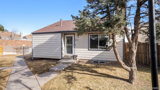 view of front of property featuring entry steps, fence, and a front yard